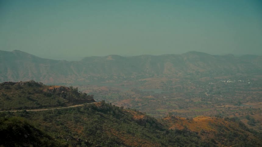 A slow panoramic view of a vast, arid mountain range with a winding road cutting through the hills