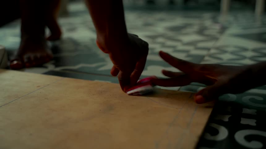 A close-up of two people's hands playing a flicking game with a small game piece on a wooden board