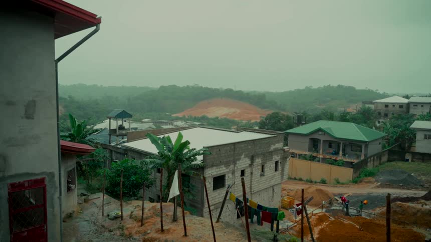 A misty view of a developing village nestled in green hills on an overcast day