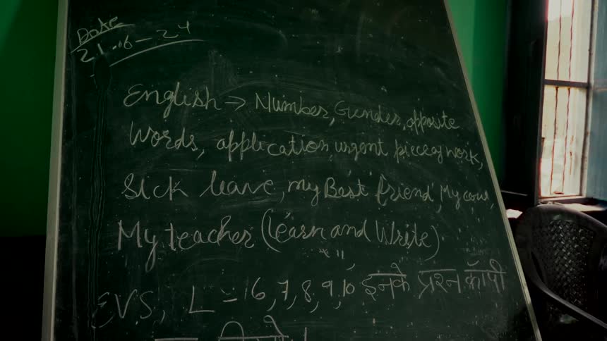 Close up of an Indian classroom chalkboard with English and Hindi lessons handwritten in chalk