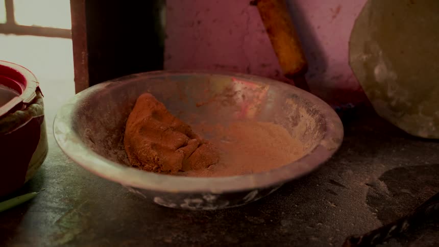A bowl of fresh dough and flour rests on a rustic kitchen counter, ready for baking