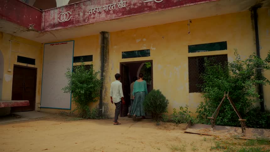 A slow motion shot of a group of people walking into the Tarun Bharat Sangh community center in rural India