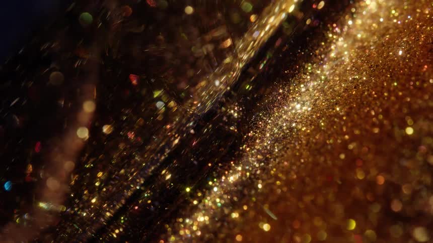 A mesmerizing close-up of golden glitter particles gently flowing and twinkling in slow motion