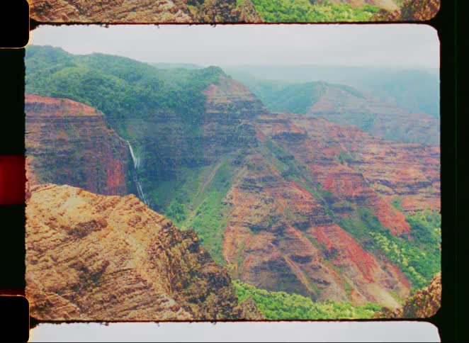 A retro 8mm film aesthetic with light leaks and grain shows the majestic Waimea Canyon and its waterfall