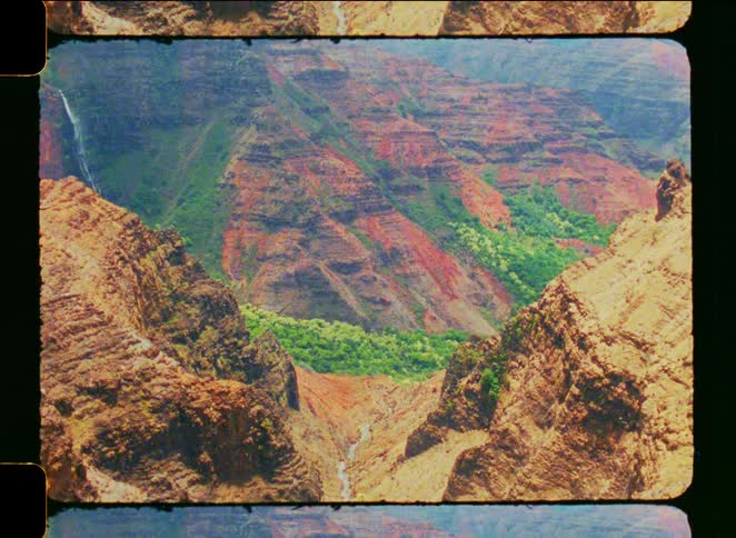 A vintage film pan reveals the stunning and colorful Waimea Canyon in Kauai, Hawaii, with a waterfall in the distance