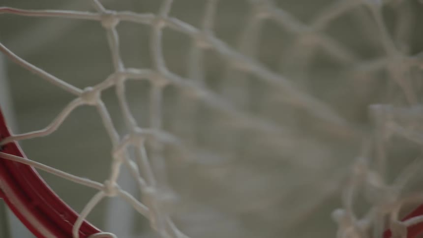 An upward-looking, slow-motion shot of a basketball swishing through the net from directly underneath