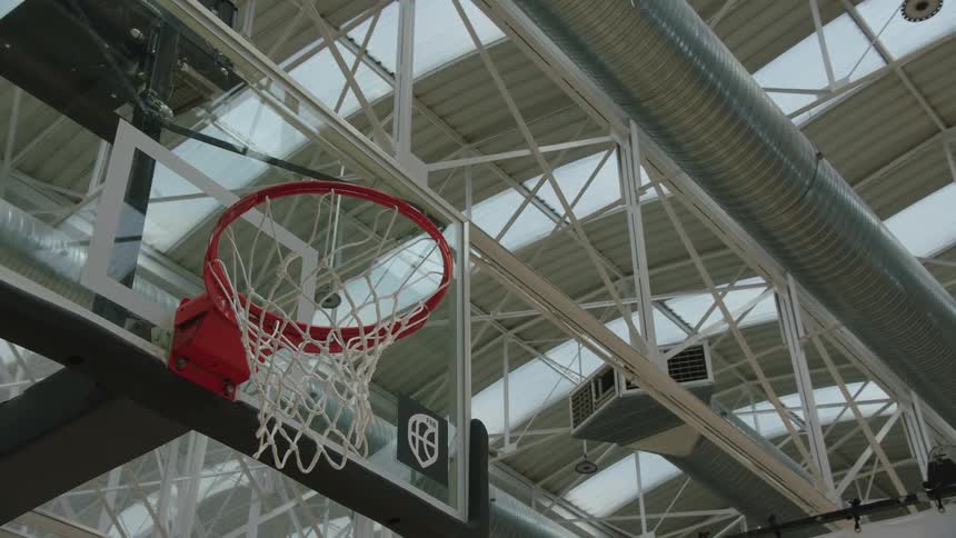 A basketball flies through the air and scores, swishing through the net in a dramatic low-angle shot
