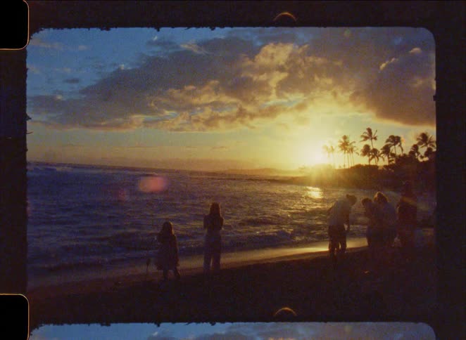 A nostalgic film captures a group of people silhouetted against a golden sunset on a tropical beach