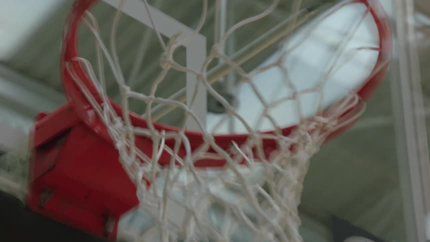 Slow-motion close-up of a basketball swishing through the net on an indoor basketball court