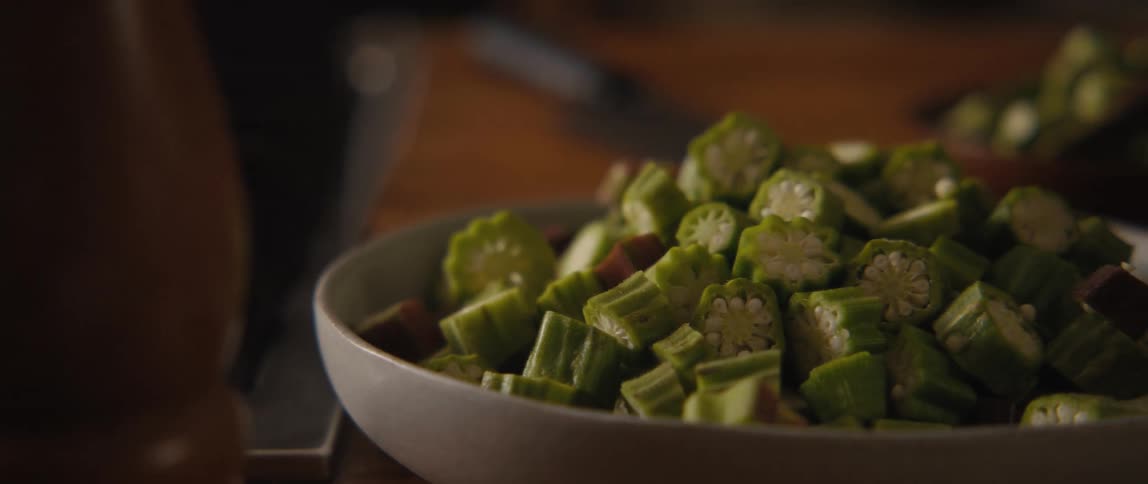 A slow pan reveals a bowl full of freshly chopped okra ready for cooking