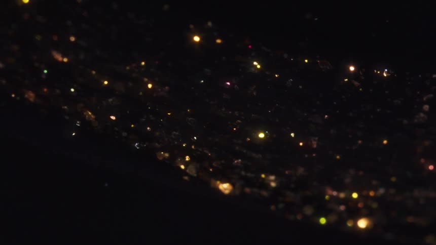 Abstract shimmering gold particles float like a galaxy against a dark background