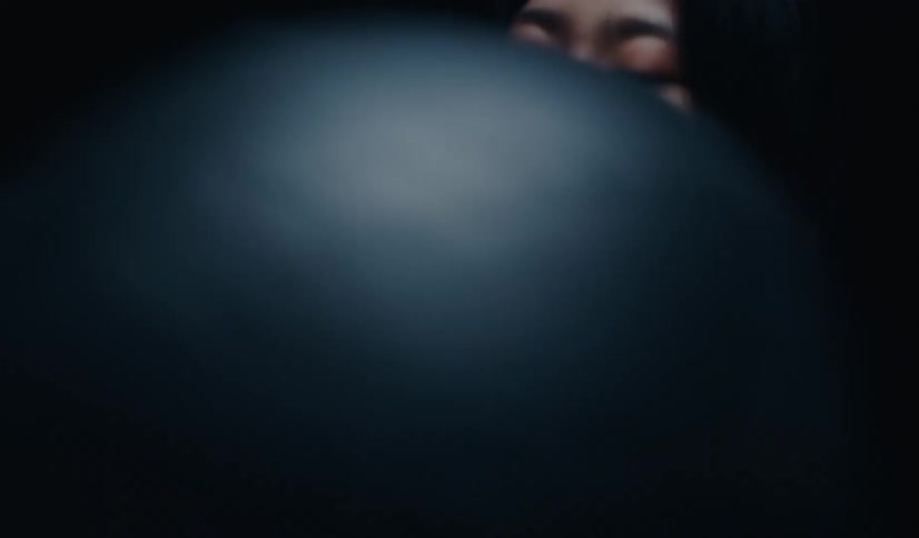 An intense slow-motion close-up of a focused Asian woman exercising on a workout machine