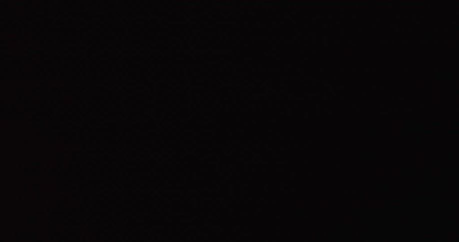 A muscular athlete breathes heavily while performing an intense dumbbell workout in a dark room under dramatic red lights