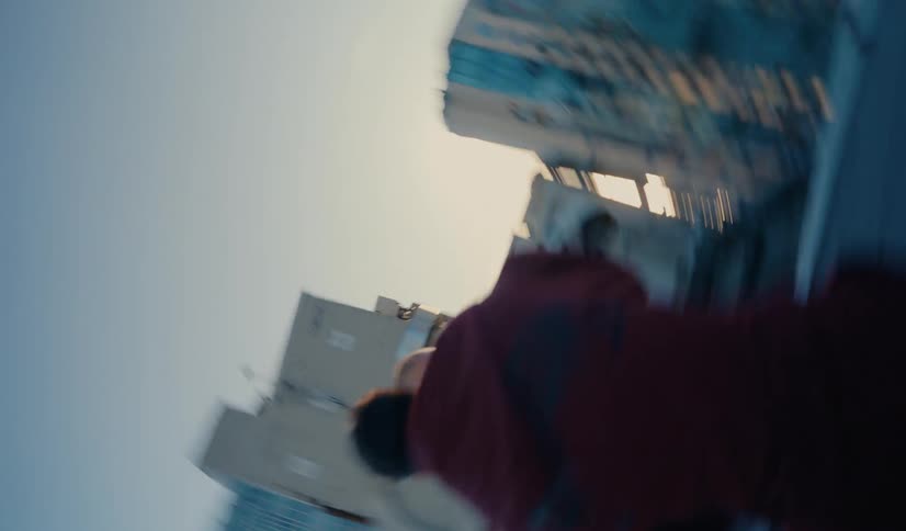 Dizzying 360-degree rotating shot of two men boxing on a rooftop with the city skyline behind them