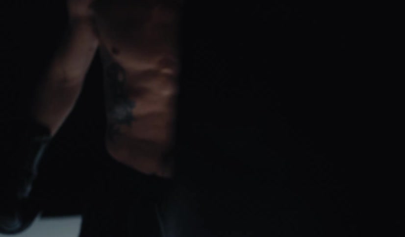 In a dimly lit space, a focused and muscular boxer throws powerful punches in a dramatic slow-motion sequence