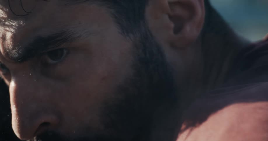 An extreme close-up, slow-motion shot of a man's intense, focused gaze during a moment of extreme physical exertion