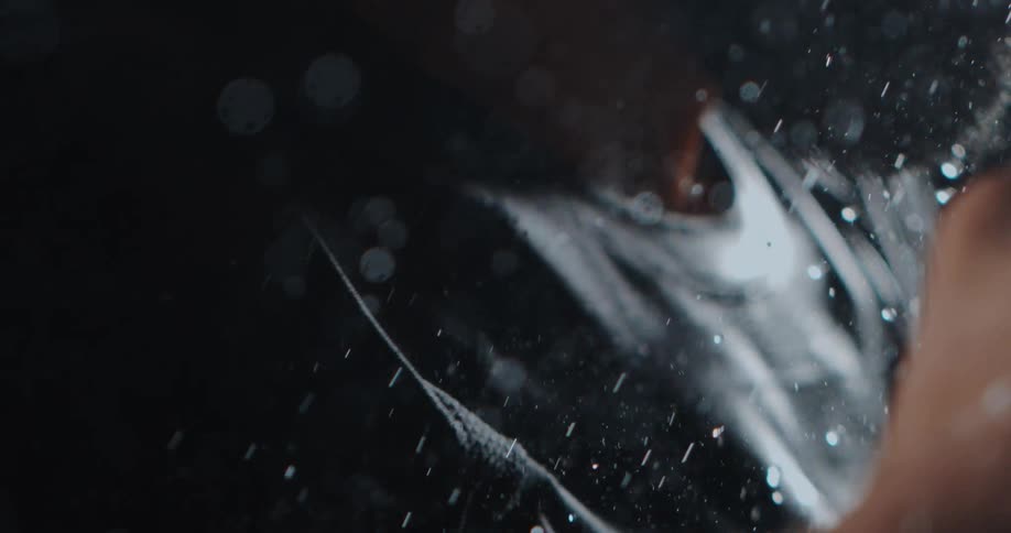 Water is wrung from a black athletic shirt in a dramatic close-up slow-motion shot against a dark background