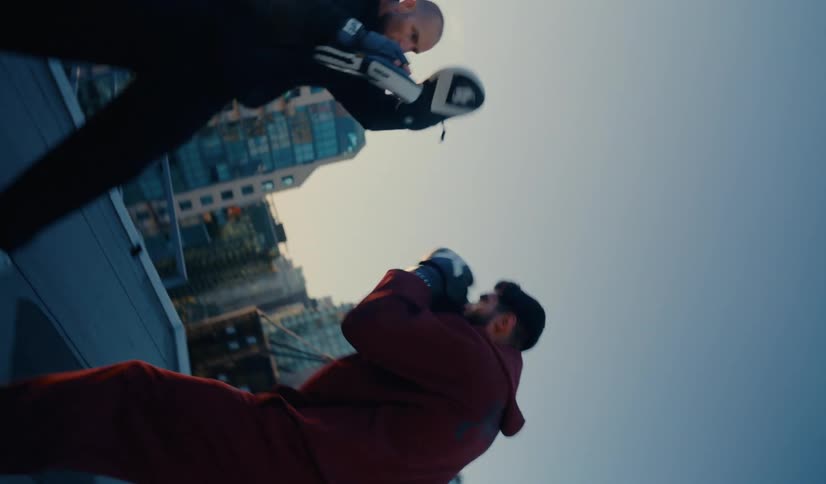Dynamic rotating slow motion footage of a boxer and his coach sparring on a city rooftop at sunrise