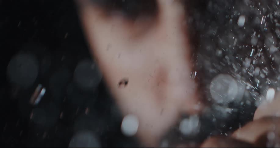 Close up of an out of focus person with snow falling heavily in super slow motion