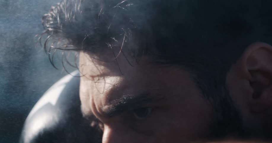 A dramatic super slow-motion close-up of an athlete's intense eyes, with steam rising from his head after a strenuous workout