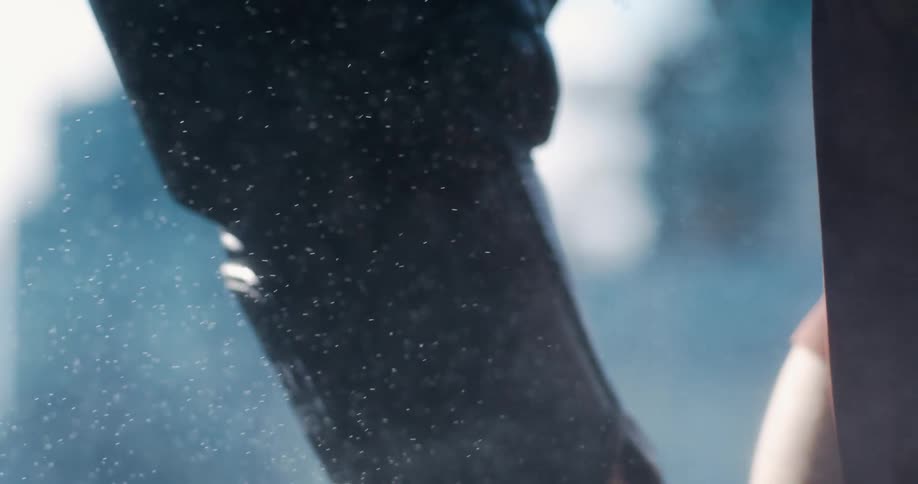 A close-up slow-motion shot of a coach intensely training a boxer in a dusty, sunlit gym