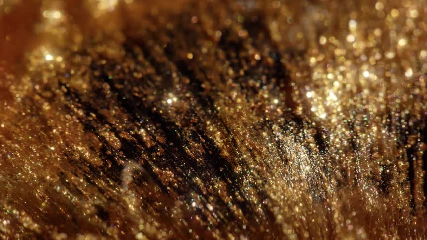 A mesmerizing macro shot of shimmering gold and black liquid paint flowing slowly with sparkling glitter