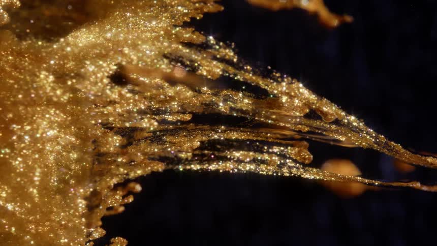 A mesmerizing macro shot of golden glitter forming ethereal, web-like tendrils in a dark, viscous fluid