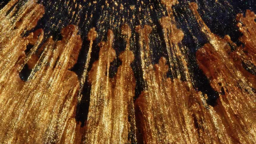 Streams of shimmering golden glitter flow upwards in a mesmerizing abstract display against a dark background