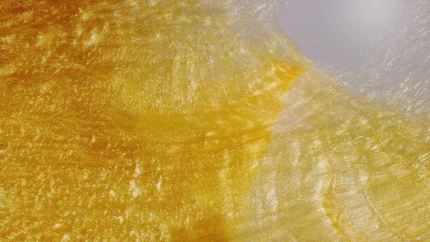 A mesmerizing macro shot of shimmering golden glitter liquid flowing slowly in abstract patterns