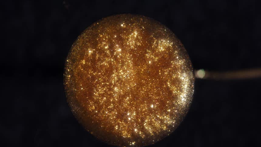 A mesmerizing macro shot of golden glitter swirling within a crystal ball on a dark background