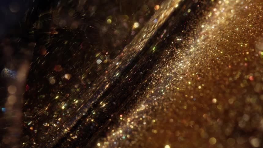 Golden glitter particles twinkle and float in a dark liquid, creating a magical abstract background
