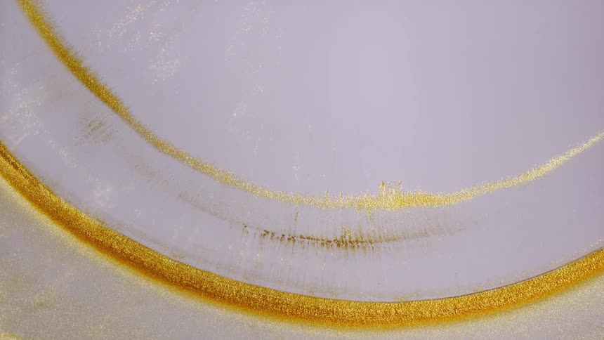 Shimmering golden curves gracefully flow across a smooth, light lavender background in a mesmerizing abstract display