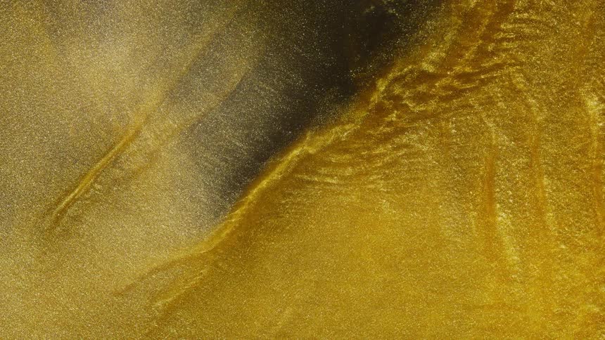 Shimmering golden glitter flows in slow motion, creating a mesmerizing and luxurious abstract background
