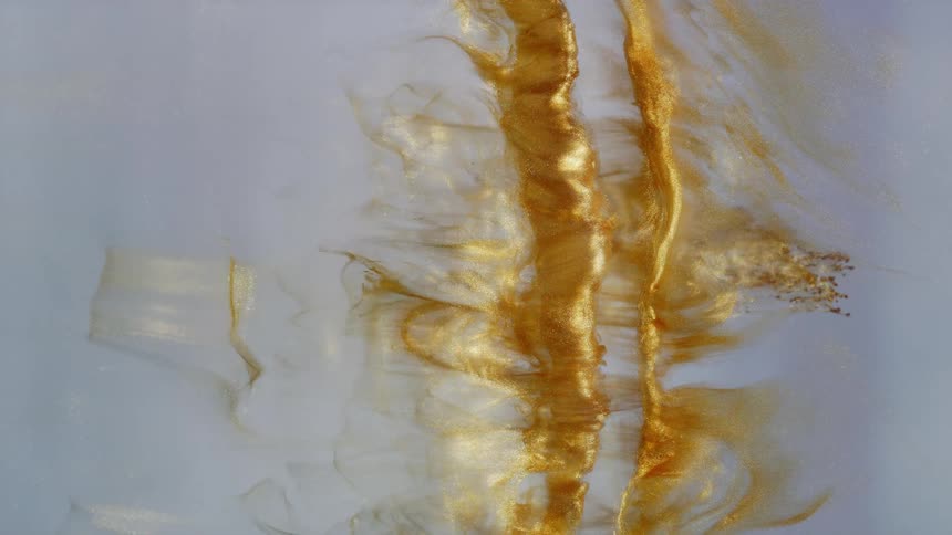 Shimmering gold liquid creates a mesmerizing abstract river as it flows through a milky white substance