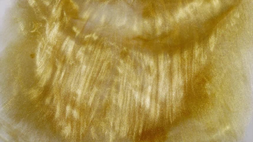 Hypnotic background of shimmering gold liquid slowly swirling and creating abstract patterns