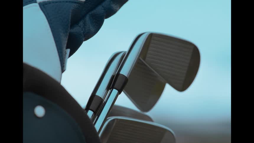 A close up slow motion shot of a hand in a golf glove selecting an iron from a golf bag