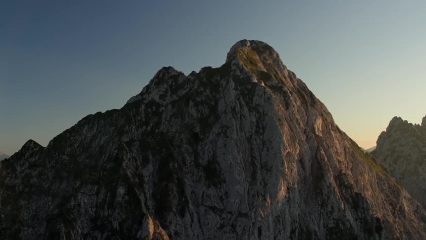 The sun illuminates a mountain peak at dawn