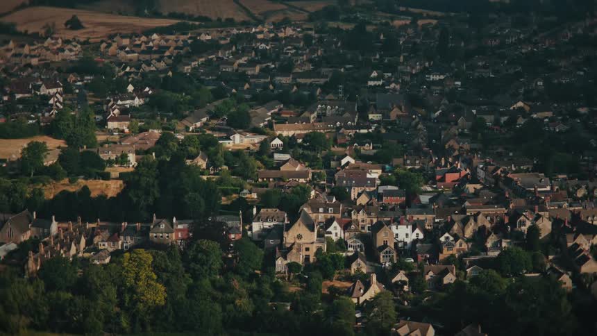 A high-angle time-lapse of sunlight and shadows moving across a quaint English town nestled in the rolling countryside