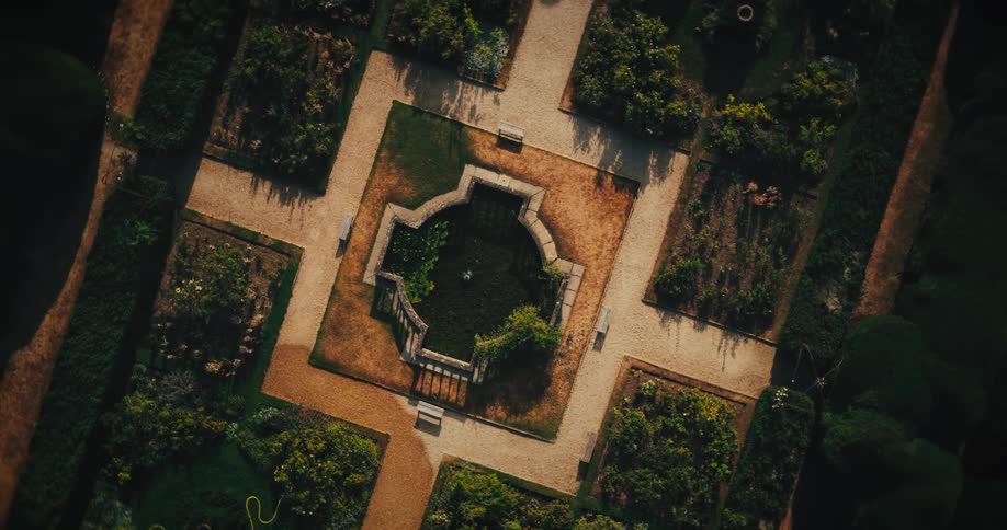 A slow aerial ascent reveals the intricate geometric design of a formal garden with a central pond