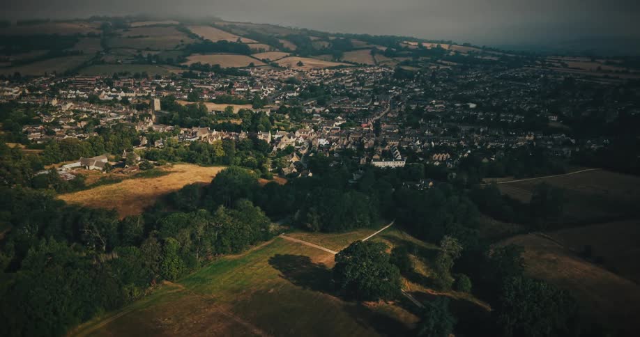 A cinematic aerial shot with a unique spin transition flies over the lush countryside towards a quaint English village
