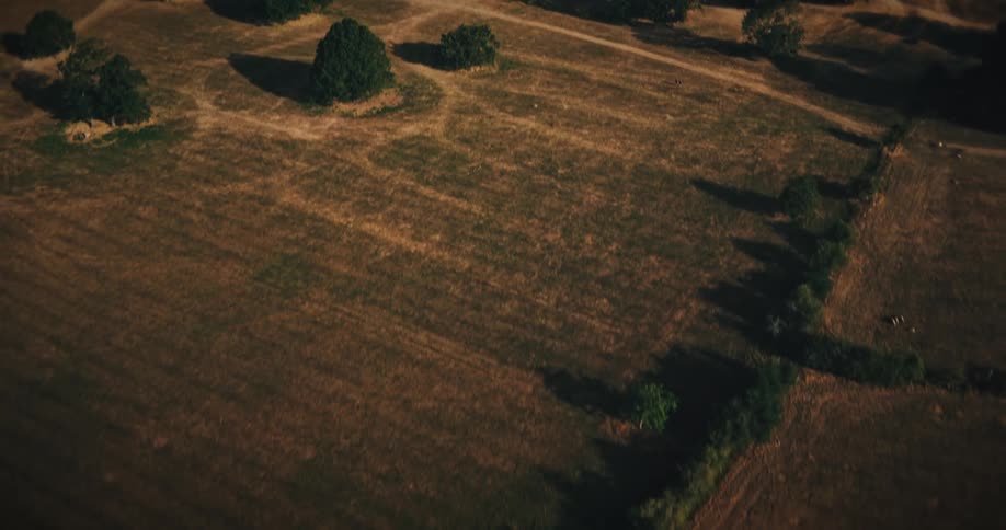 A dramatic aerial shot pulls back from a historic English castle, revealing the vast, sunlit rural landscape and fields below