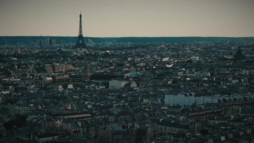 A static aerial view of the Paris skyline featuring the iconic Eiffel Tower and countless rooftops stretching to the horizon