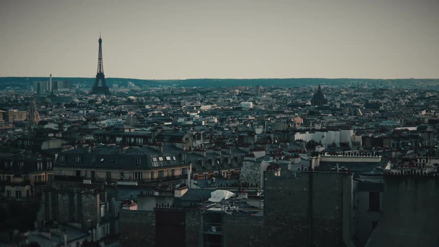 A cinematic slow-moving aerial shot reveals the iconic Eiffel Tower and the expansive rooftops of Paris, France