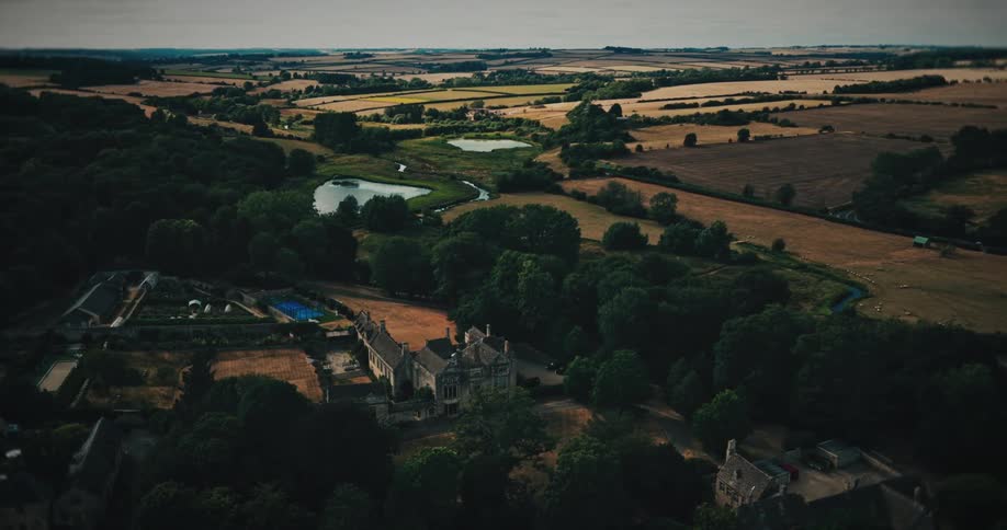 A majestic aerial shot reveals a grand historic estate surrounded by the idyllic and sprawling English countryside