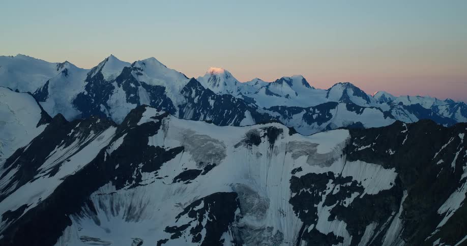 The first light of dawn kisses the snow-capped peaks of a majestic mountain range