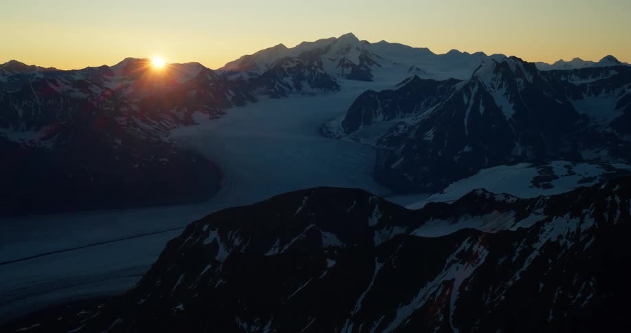An epic sunrise over a vast and majestic snow-covered mountain range with glaciers