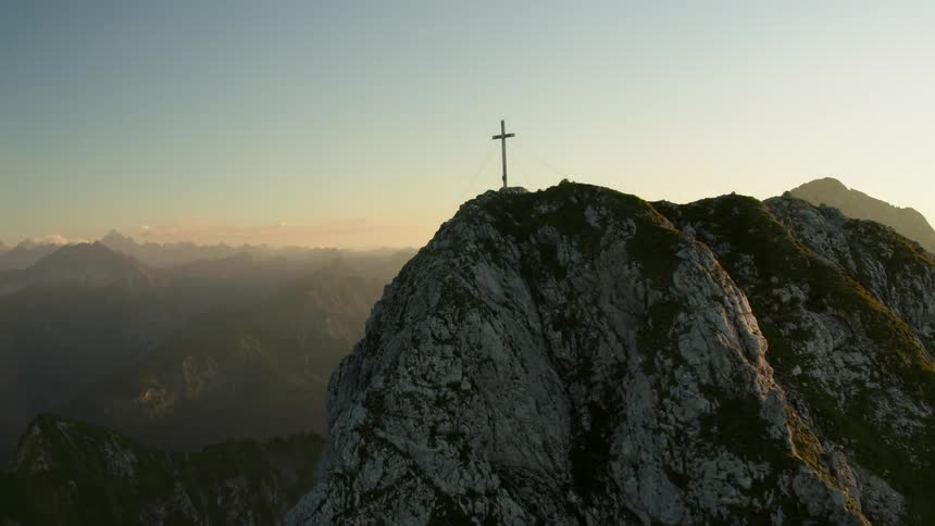 Cross on top of a mountain at sunrise