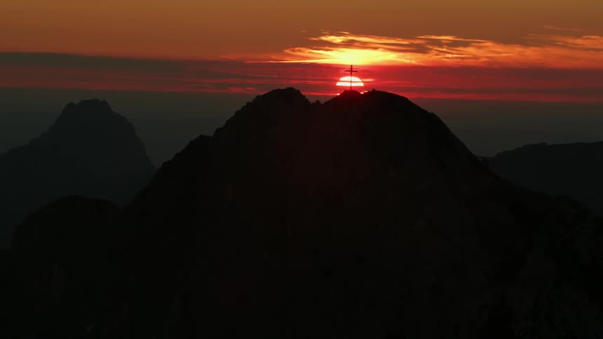 A cross is on top of the mountain at dawn