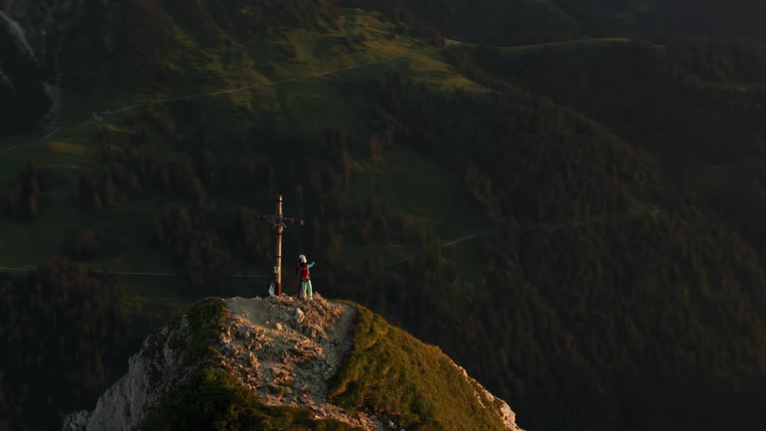Two people hike up to the cross on a mountain