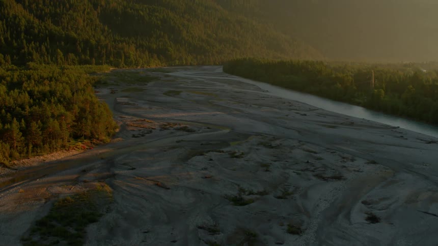 A muddy river bed winds through the trees and hills